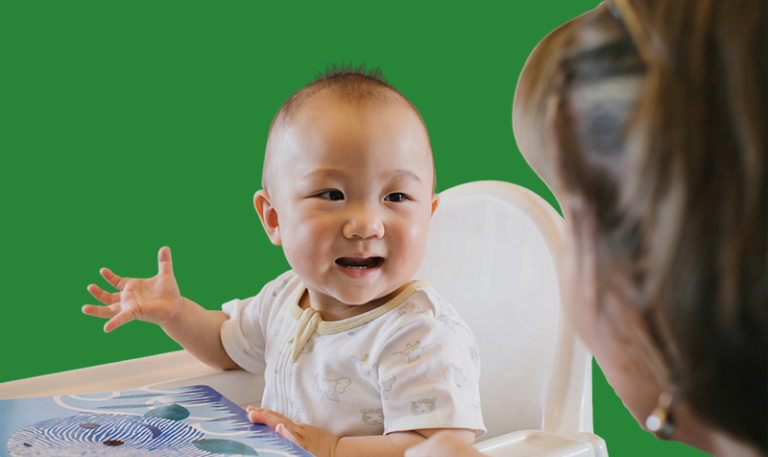 Young child in a high chair engaging in an interactive play experience that supports learning and development.